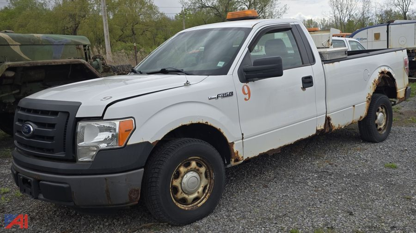 Ford F-150 XL pickup truck in white; single cab, long bed, with rust along fender arches and wheels; orange beacon on roof; label 9 on door; utility style.