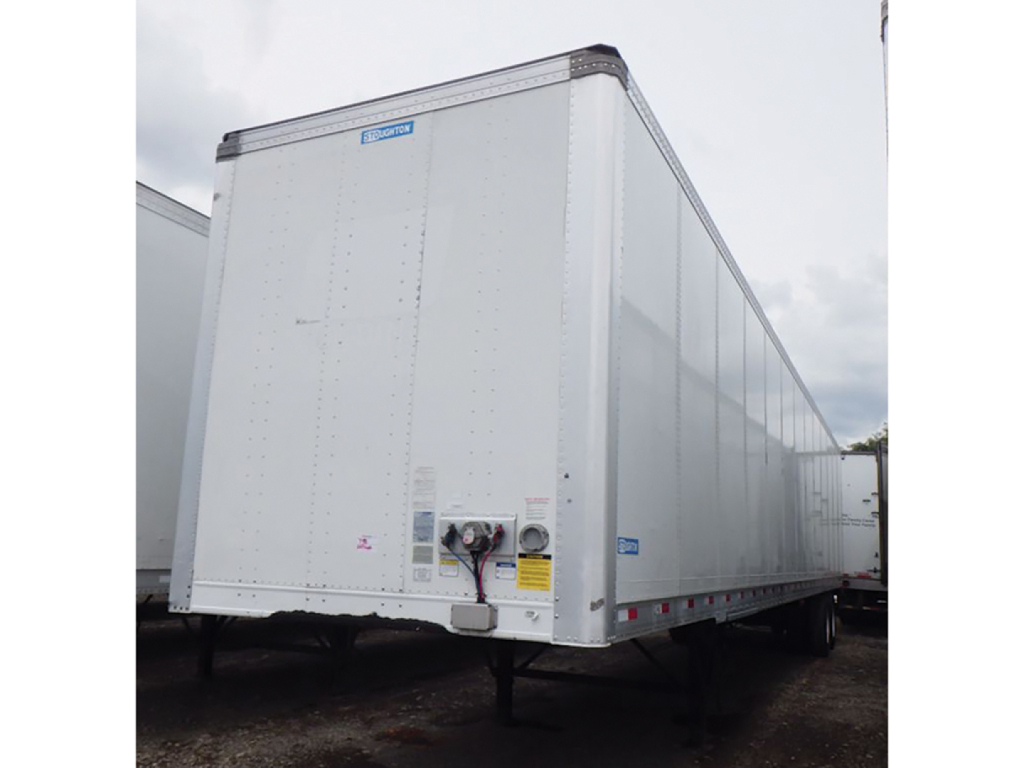 Stoughton plate van trailer showing rear with electrical connection and safety decals, aluminum exterior, high-visibility reflective tape along lower edge.