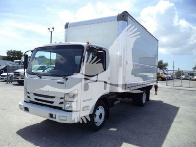 Isuzu NPR HD box truck in a dealership lot. Front badge and grille visible, large box cargo area. Windshield shows reflections. Side mirror and wheel visible.