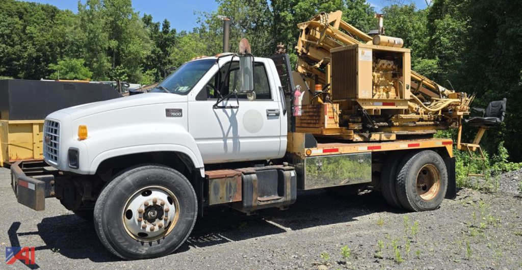 GMC C7500 utility truck with crane/lift on flatbed, side view showing white cab and equipment on bed, used condition.