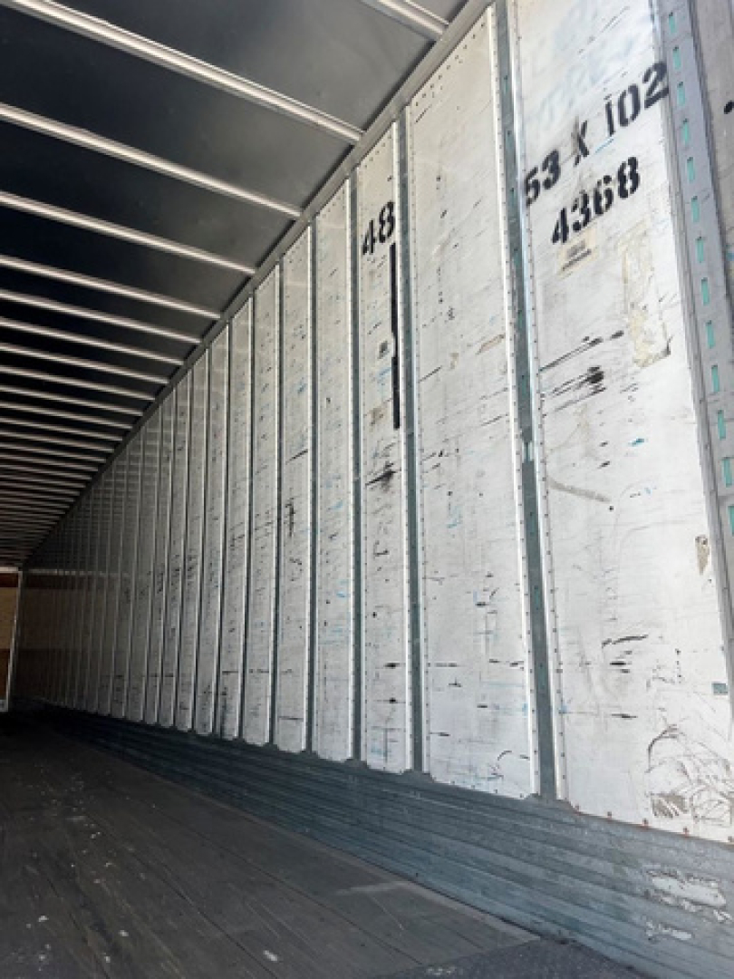 Trailer interior side wall with vertical metal panels and numbers, showing the inside of a cargo van trailer.