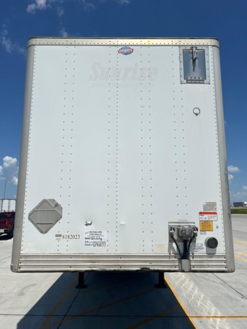 Utility van trailer rear showing solid white exterior, with latches, vents, and safety decals.