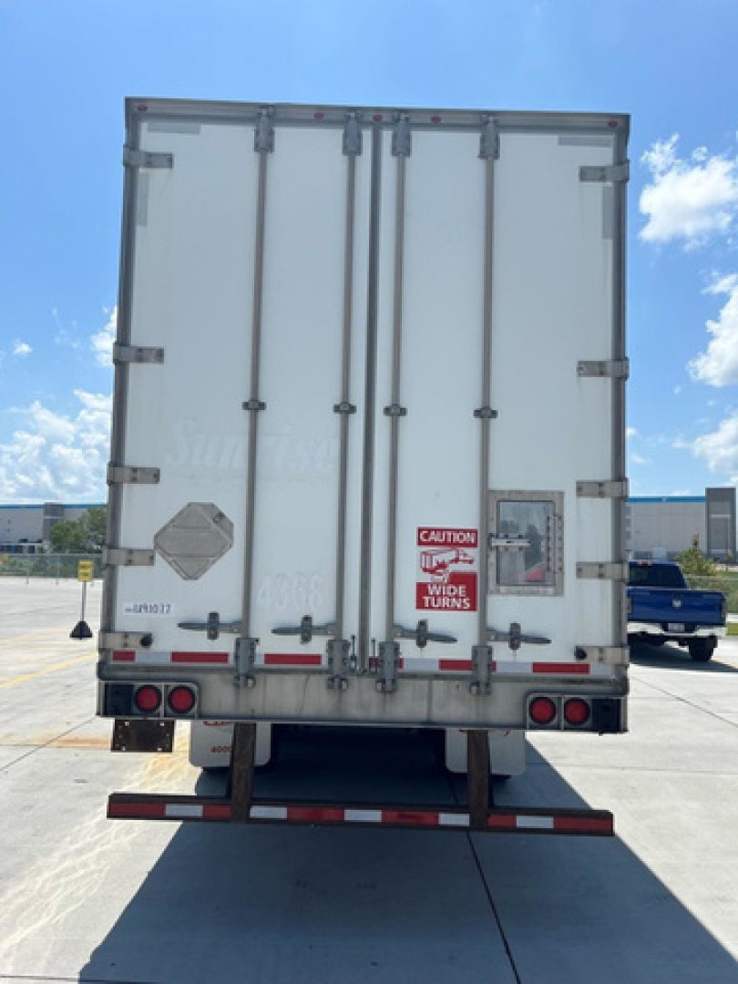 Rear view of a 2014 utility van trailer with closed double doors, warning labels, taillights, and a license plate area visible.