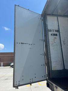 Trailer van rear door open showing interior wall and door hinges, side of trailer marked with 53 X 102 4366