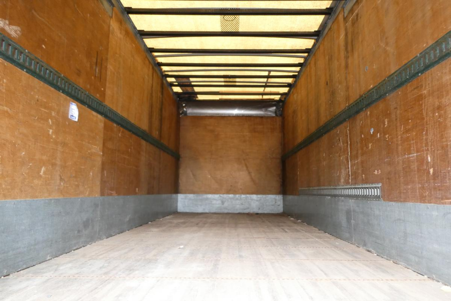 Interior of an empty box truck trailer with wood walls and metal rails, empty cargo area, elevated roof ribs visible