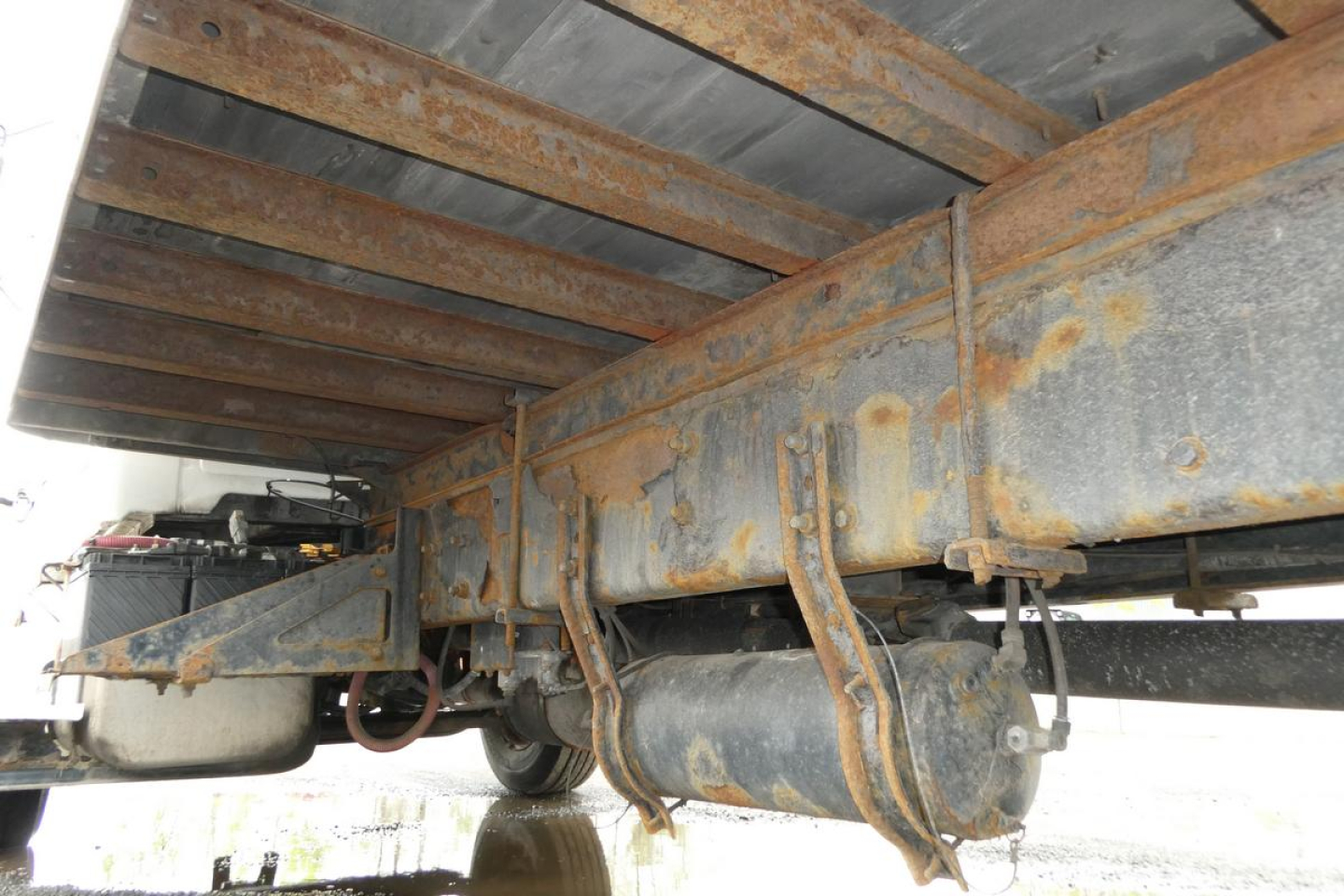 Underbody view of a 2006 Sterling ACTERRA truck showing rust on frame rails and cylindrical components; trailer hitch area and underside hardware visible.