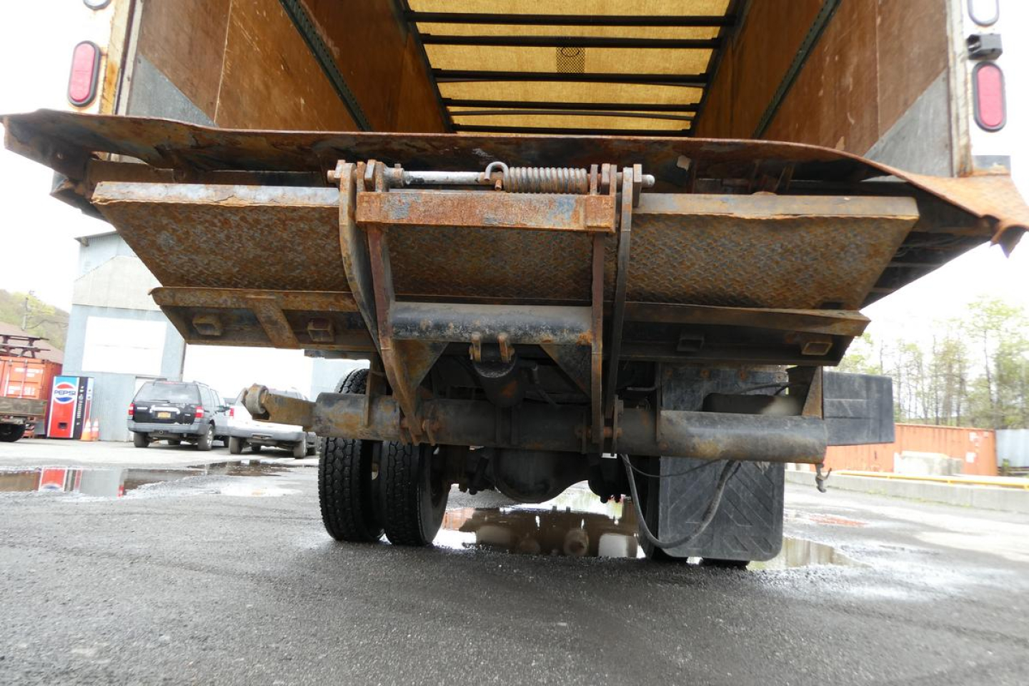 Sterling Acterra truck rear view showing rusty dump bed frame and undercarriage; visible components include the tailgate hinges, frame, and rear tires.