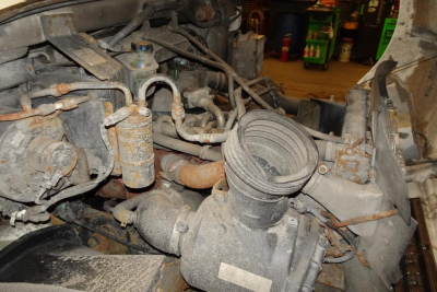 Engine bay with intake piping and components in view; various hoses, fittings, and a cylindrical filter canister visible.