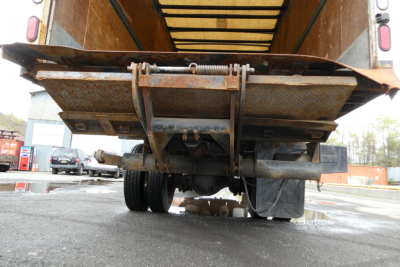 Sterling Acterra truck rear view showing rusty dump bed frame and undercarriage; visible components include the tailgate hinges, frame, and rear tires.