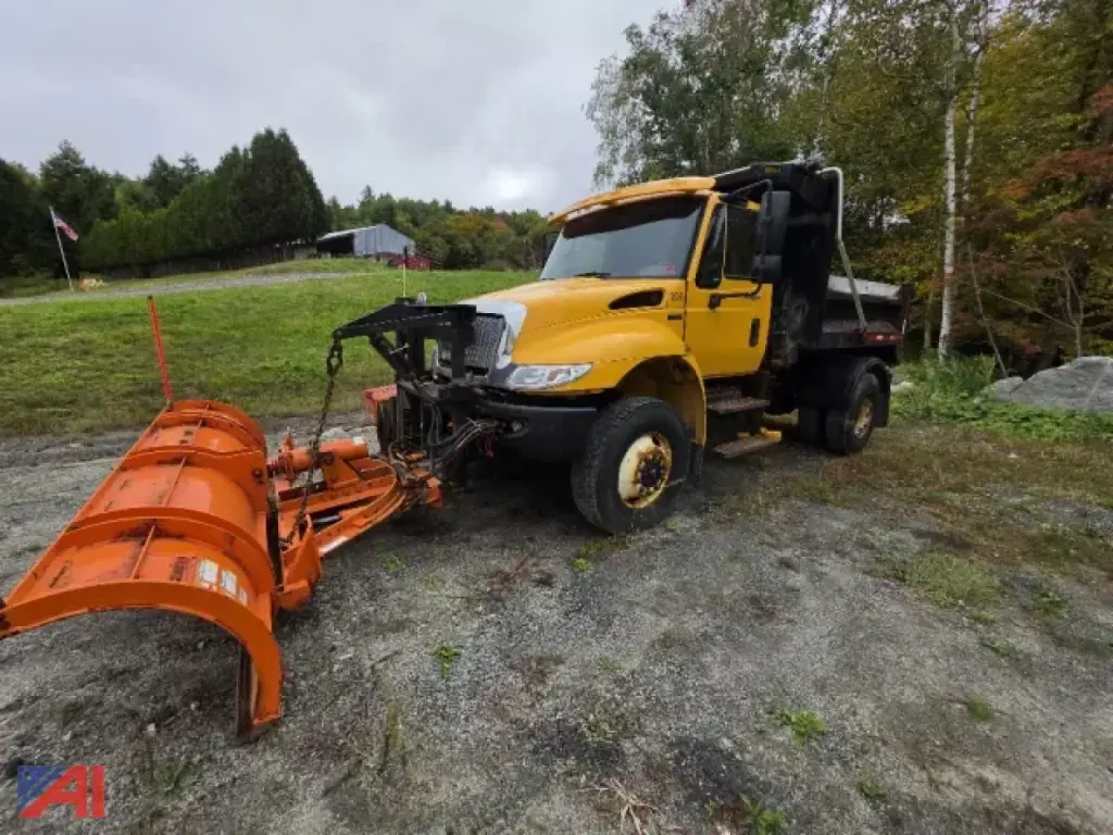 International 4300 dump truck with plow and wing attachment showing front grille and yellow cab