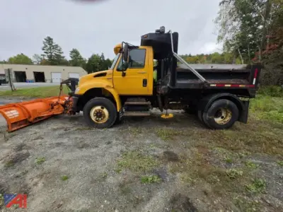 Dump truck with plow and wing attachment showing cab, flatbed, and snow plow in front.
