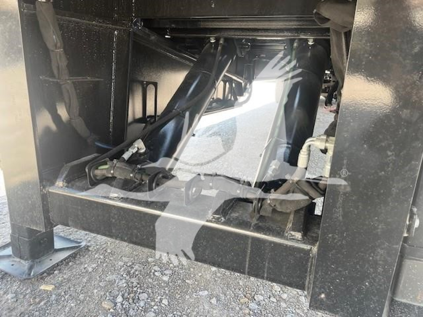 Trailer hitch area showing hydraulic actuators and frames under a trailer (XL Specialized 110Sa) with black metal support beams and hydraulic lines.
