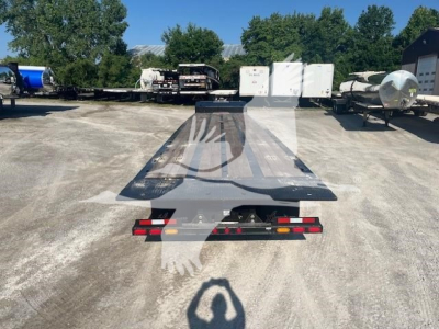 Traveling axle trailer rear view showing flatbed deck, rear lights, and hitch area.