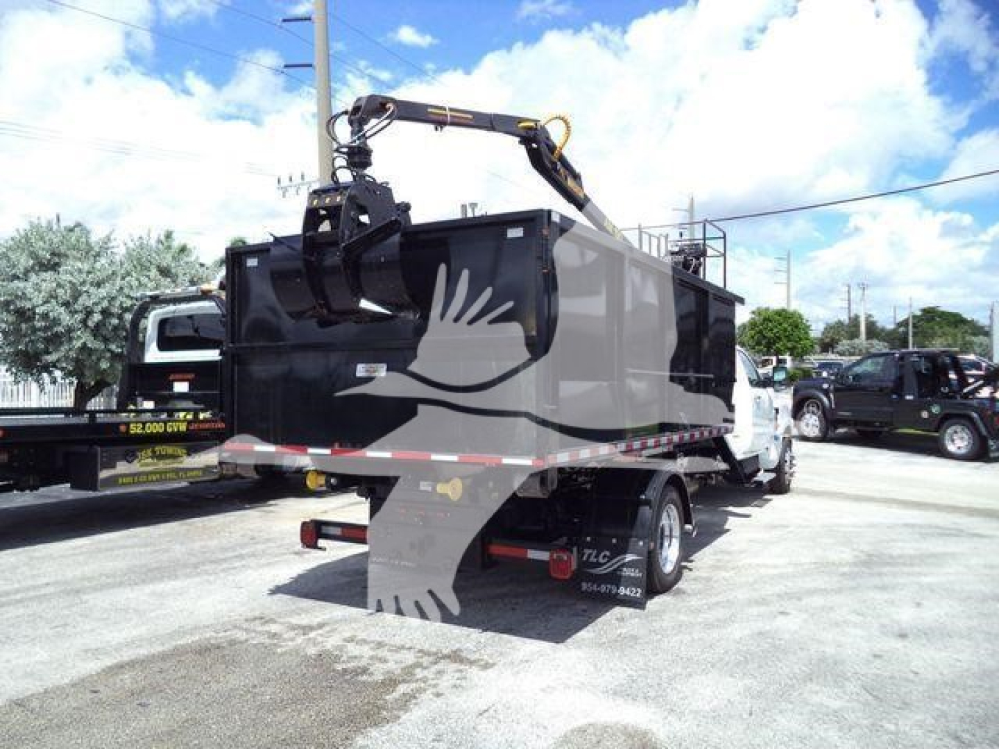 Truck bed with crane on a 2023 Chevrolet Silverado 6500HD showing a hydraulic hoist and dump body, side and rear view.