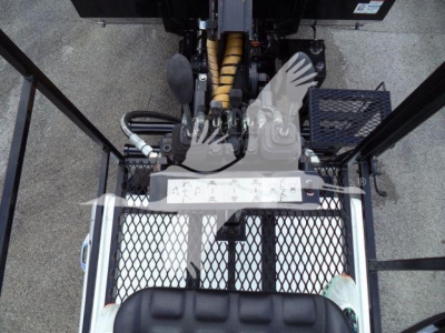 View from above of a construction truck cab area showing hydraulic levers, pedals, and operator platform with metal grate steps and rubber matting.