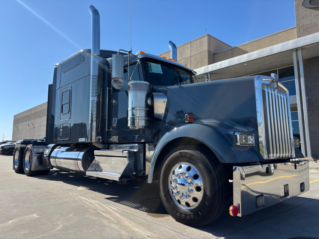 Kenworth W900L heavy-duty truck in chassis cab view showing chrome wheels and dual exhaust stacks