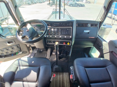 Interior cab of 2023 Kenworth W900L showing steering wheel dashboard gear shifter and controls