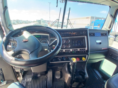 Kenworth W900L truck interior dashboard and steering wheel view with gauges and gear shifter.