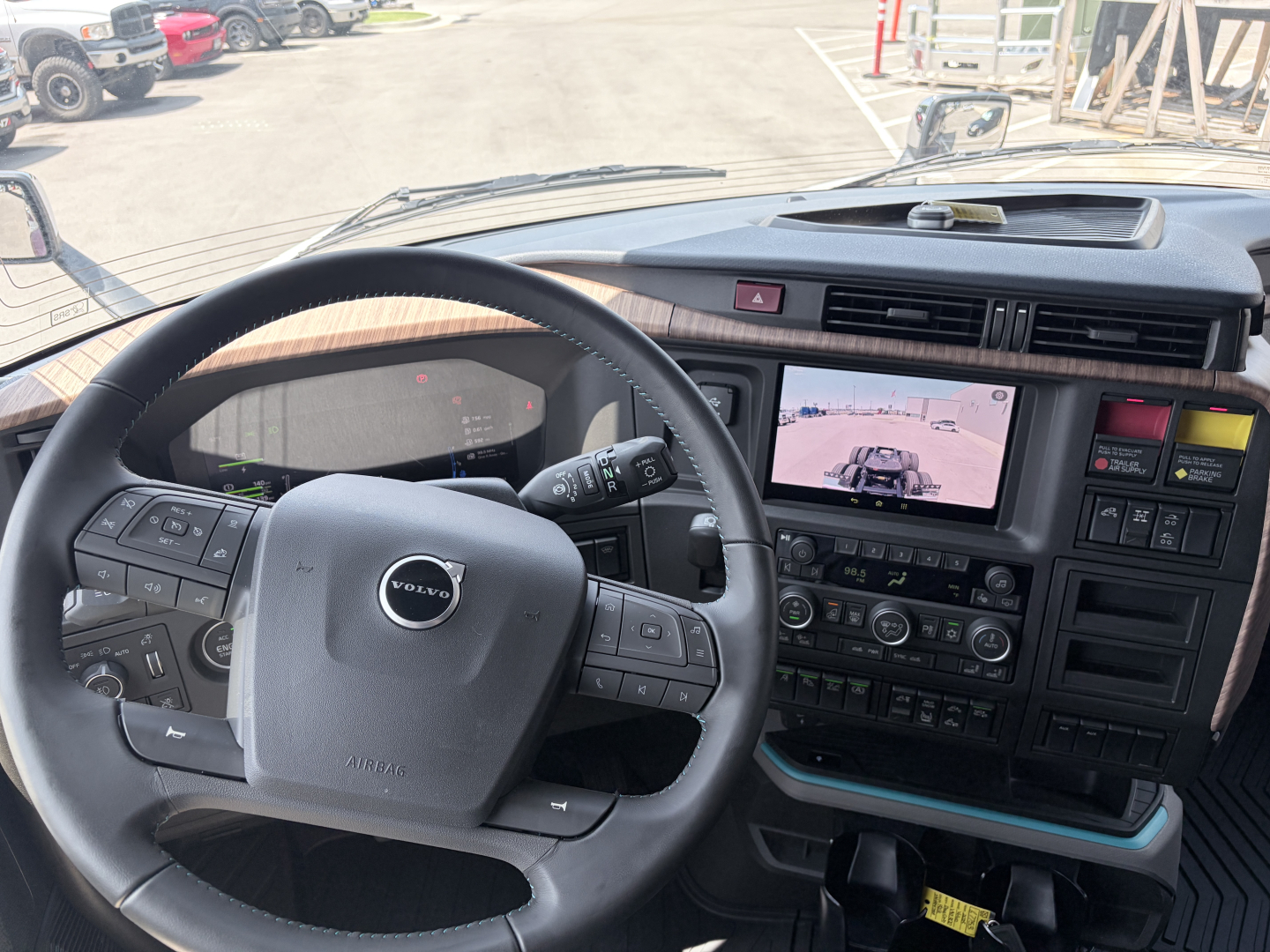 Volvo VNL truck cabin interior showing steering wheel with Volvo logo, digital dashboard, and center infotainment screen; dashboard controls and gear area visible.