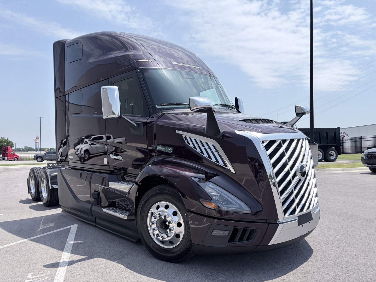 Tractor-trailer cab in dark maroon showing Volvo VNL64T860 front grille and chrome mirrors