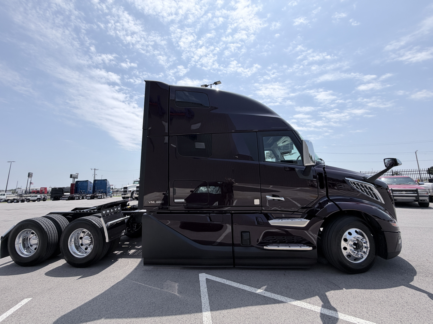 Volvo VNL64T860 cab in profile view showing black exterior, sleeper cab, chrome accents, and three rear axles with dual tires.