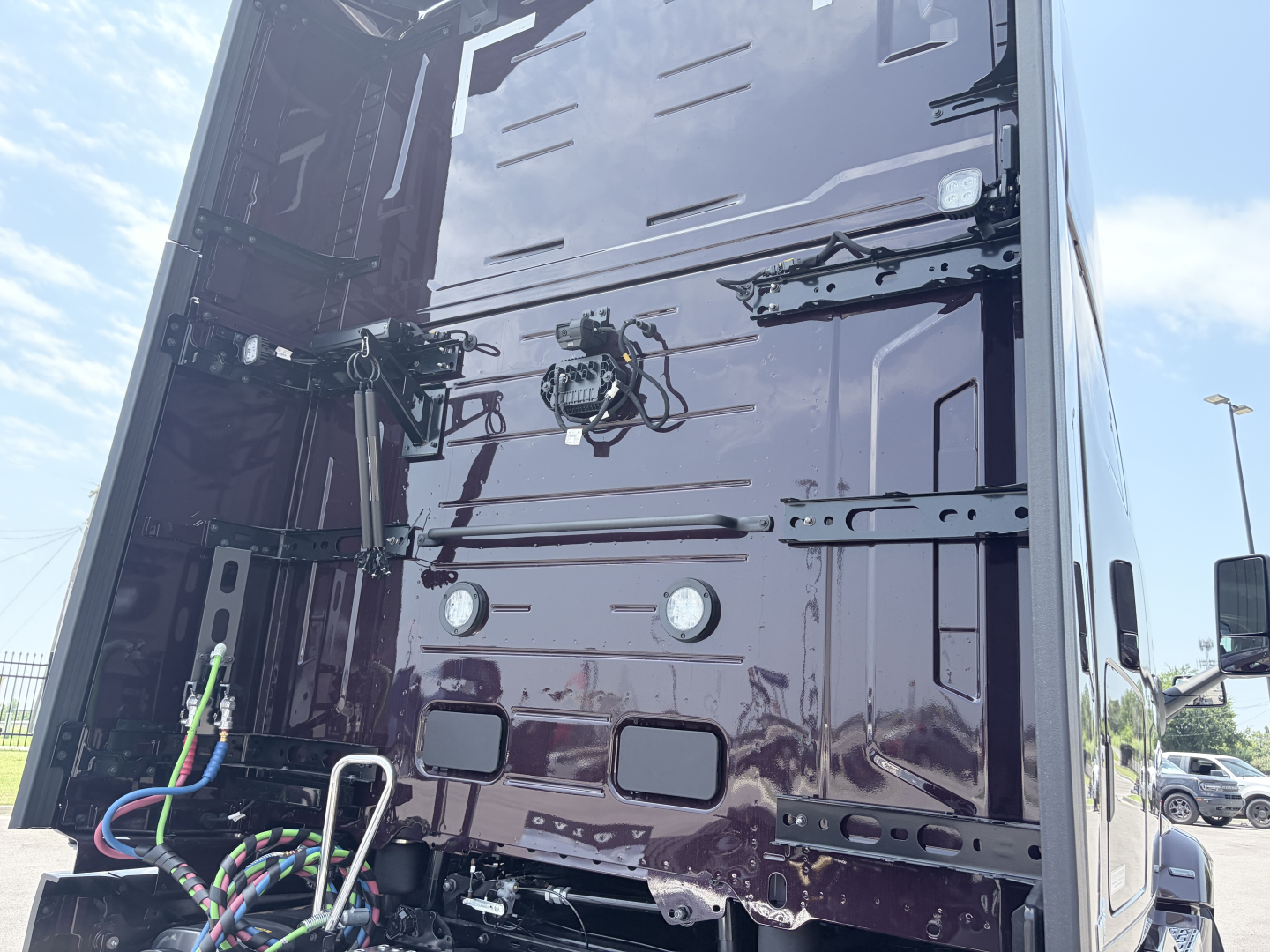 Back of Volvo truck cab panel with electrical wiring and connectors, two circular reflectors, and various panels and latches visible.
