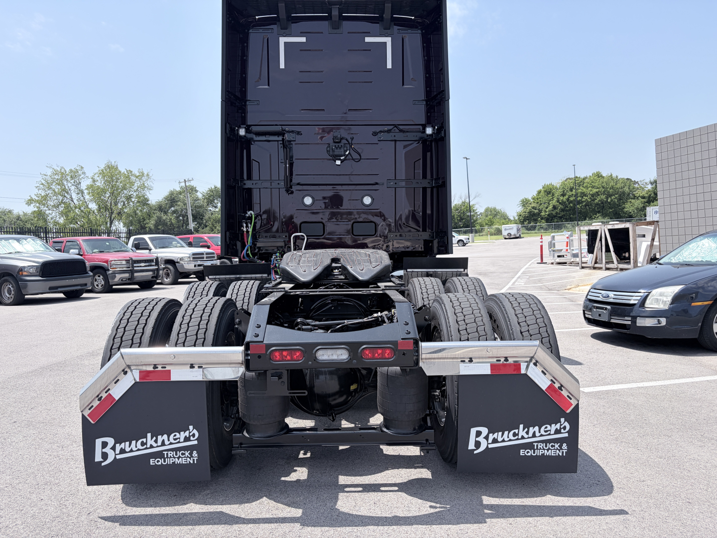 Truck rear view showing fifth wheel and dual rear axles of a Volvo VNL64T860 tractor with mud flaps and tail area visible.