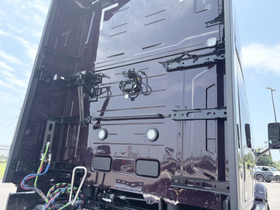 Back of Volvo truck cab panel with electrical wiring and connectors, two circular reflectors, and various panels and latches visible.