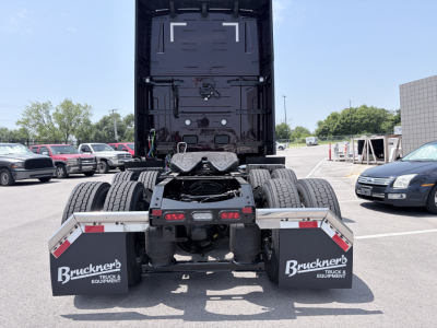 Truck rear view showing fifth wheel and dual rear axles of a Volvo VNL64T860 tractor with mud flaps and tail area visible.
