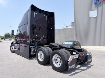 Volvo VNL64T860 tractor cab and rear chassis with dual rear axles and fifth-wheel, glossy black paint, fuel tanks and chrome wheels visible.