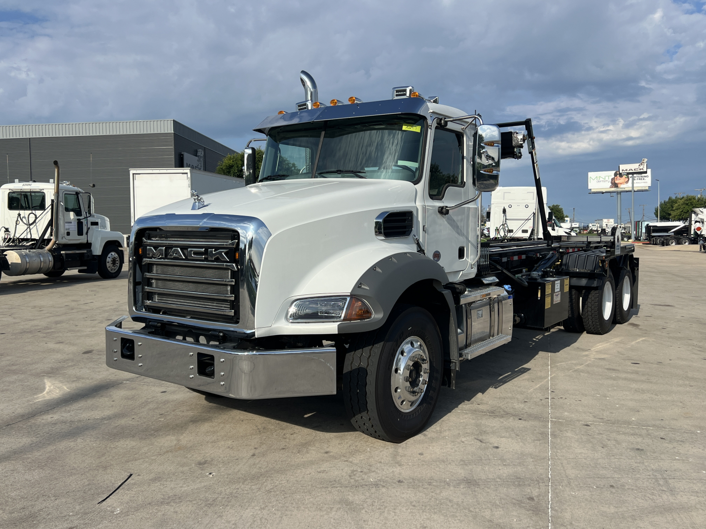 Mack GR64B truck cab and wheel showing chrome grille and front bumper with Mack emblem.
