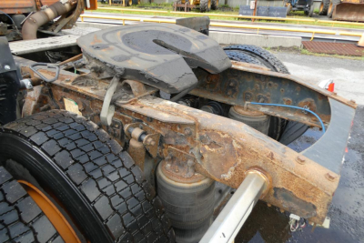 Truck chassis and fifth wheel on Freightliner Cascadia 125 cab unit showing rusty frame and dual tires with visible suspension components.