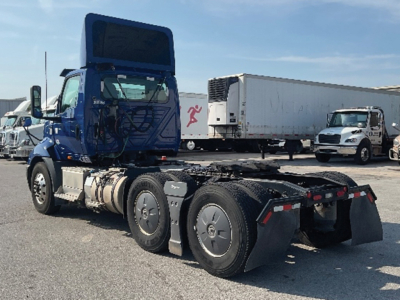 Truck cab and chassis of a blue 2020 International RH613 daycab with dual rear axles and a white trailer in background.