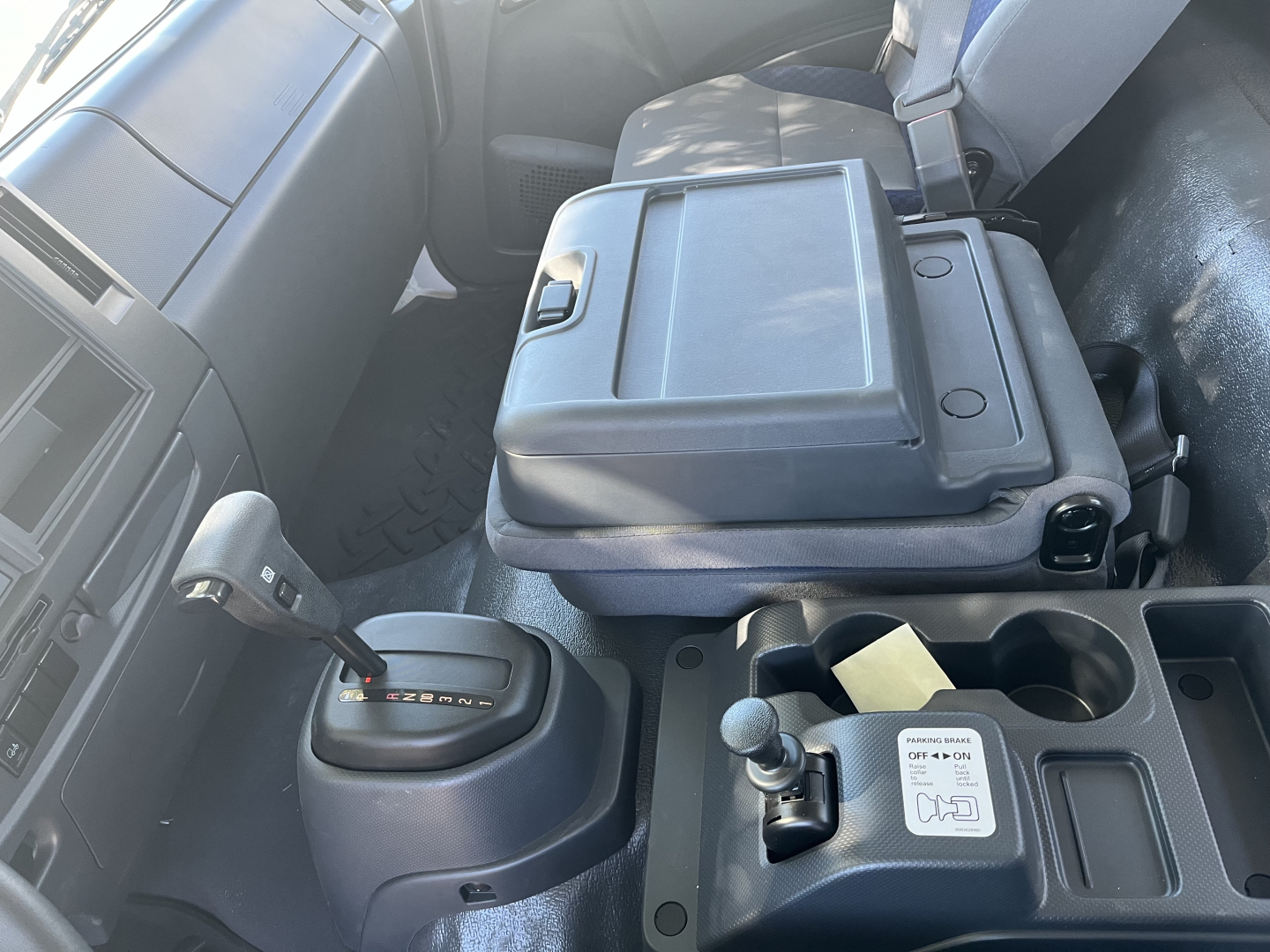 Isuzu FTR interior center console and gear selector with cup holders and storage area visible.