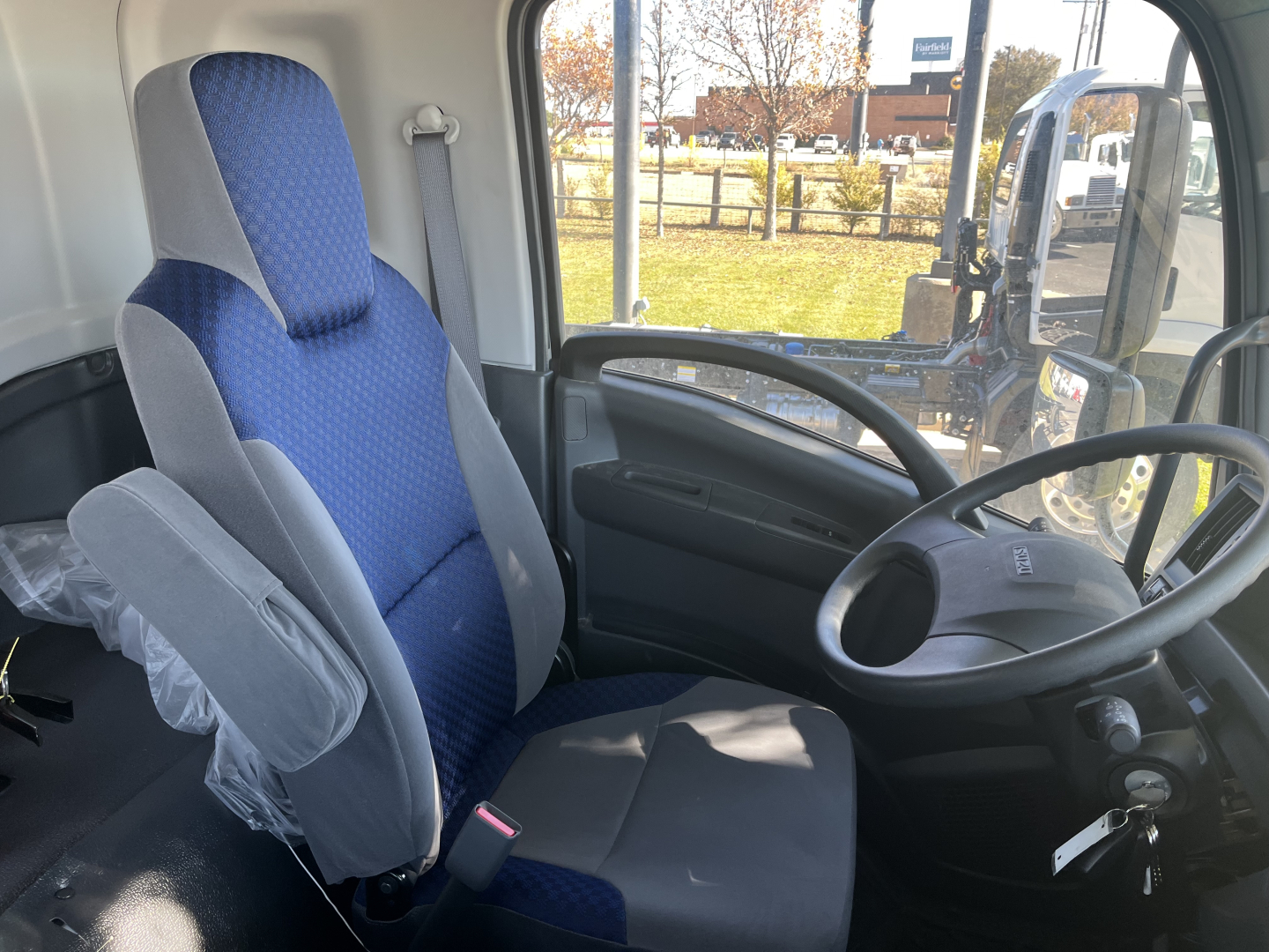 Isuzu FTR truck interior showing blue fabric driver's seat and steering wheel in-view.