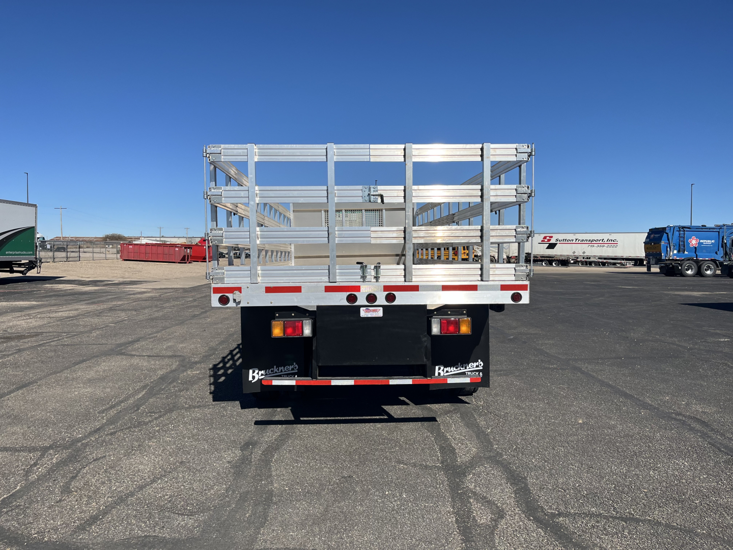 Isuzu FTR stake bed truck rear view showing metal side rails and bumper with taillights.
