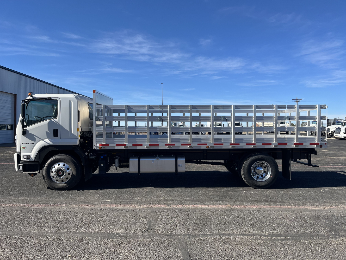 Isuzu FTR stake bed truck side view with silver cab and open-framed stake bed.