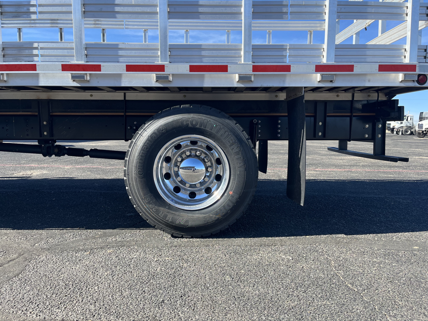 Isuzu FTR truck side showing single rear wheel and stake bed frame with reflective tape.