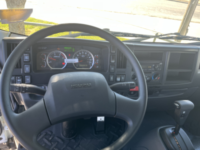 Isuzu FTR dashboard and steering wheel view from the cab showing analog gauges and control stalks.