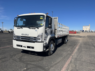 Isuzu FTR stake bed truck in yard showing front and passenger side with white cab and long stake bed.