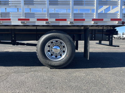 Isuzu FTR truck side showing single rear wheel and stake bed frame with reflective tape.