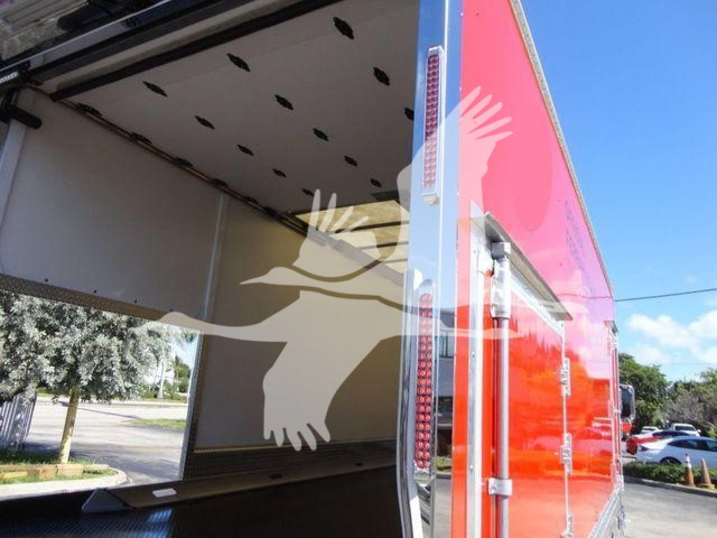 Truck bed/rollback trailer interior of a 2027 Mack MD6 with an open rear cargo area and red exterior, side doors, and support entry ramp.