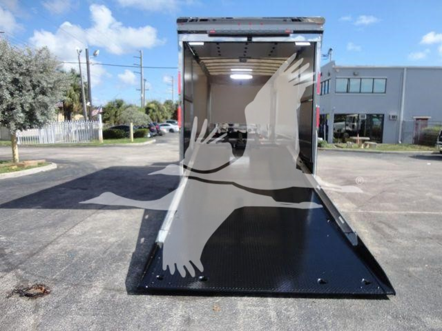 MD6 empty rollback truck with a lowered black steel ramp at the rear, interior cargo area visible, light gray walls, and a bright exterior scene.