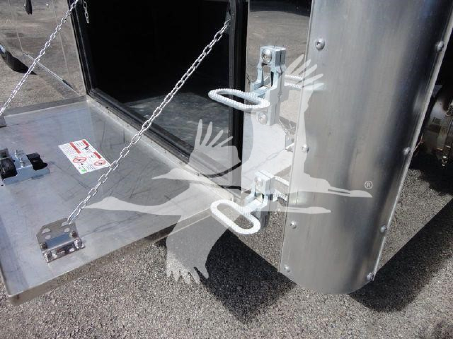 Truck component showing a metal toolbox/storage area with a chain and a latch; close-up of a towing hitch and vertical panel on a Mack MD6 rollback truck.