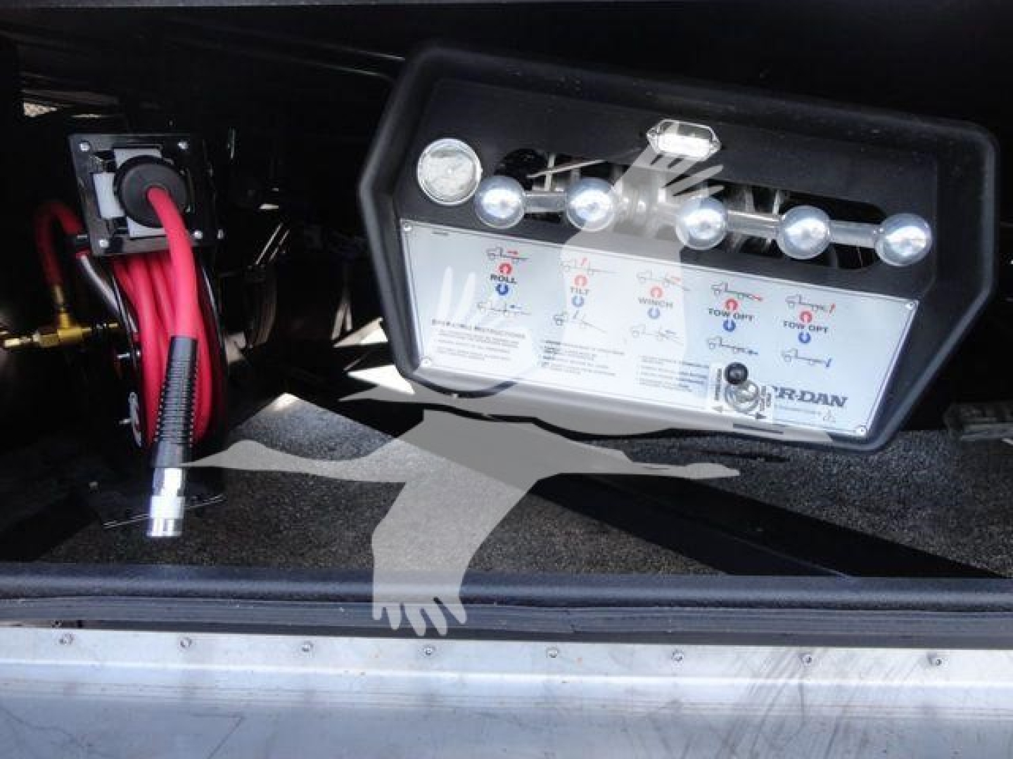 Panel showing control switches and gauges labeled for a Mack MD6 rollback tow truck. Visible text includes U, V, and warning labels with valve handles and a DRUM label.