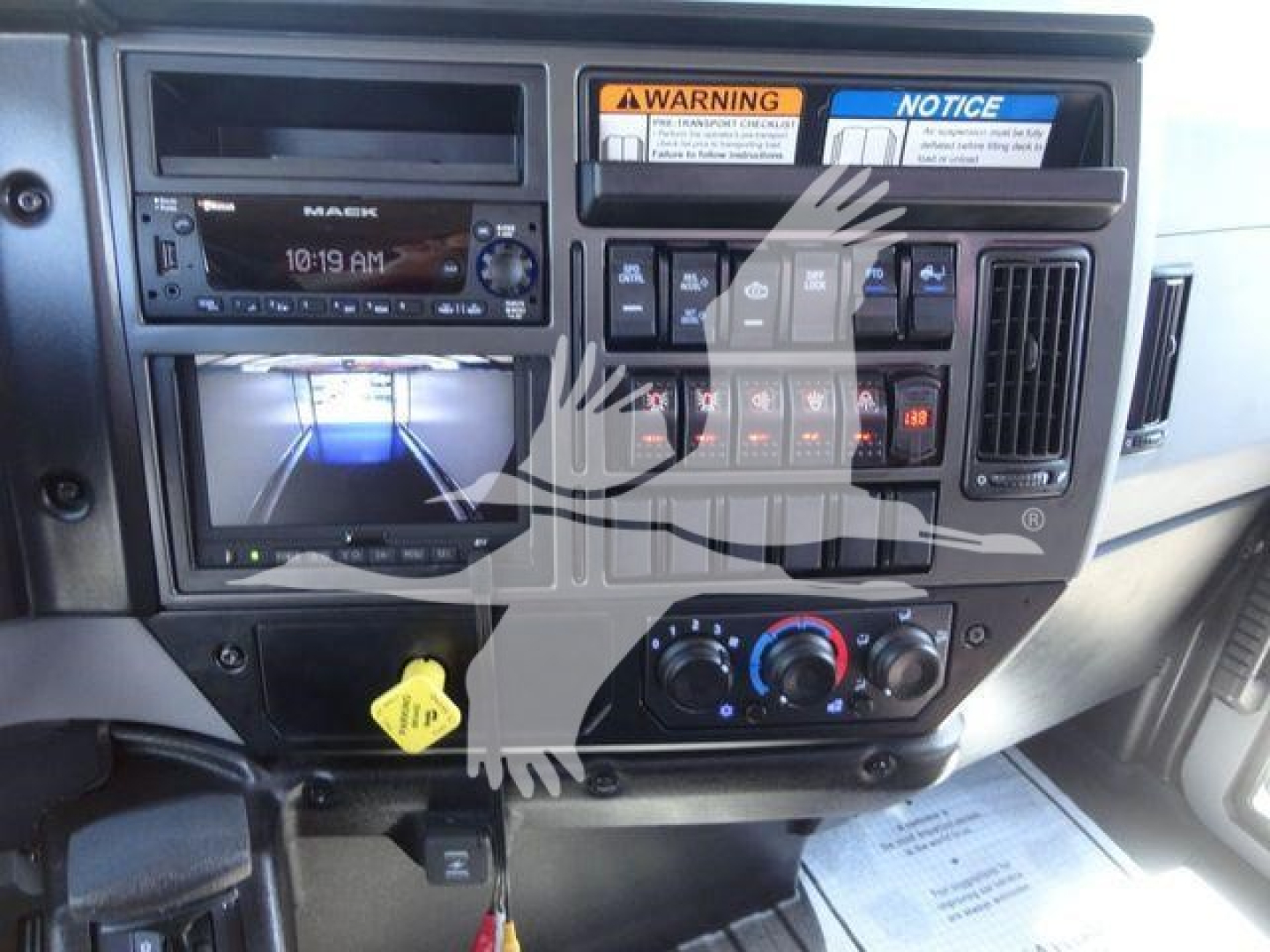 Dashboard of a 2027 Mack MD6 rollback truck showing stereo unit, control switches, climate controls, and yellow keying lure.
