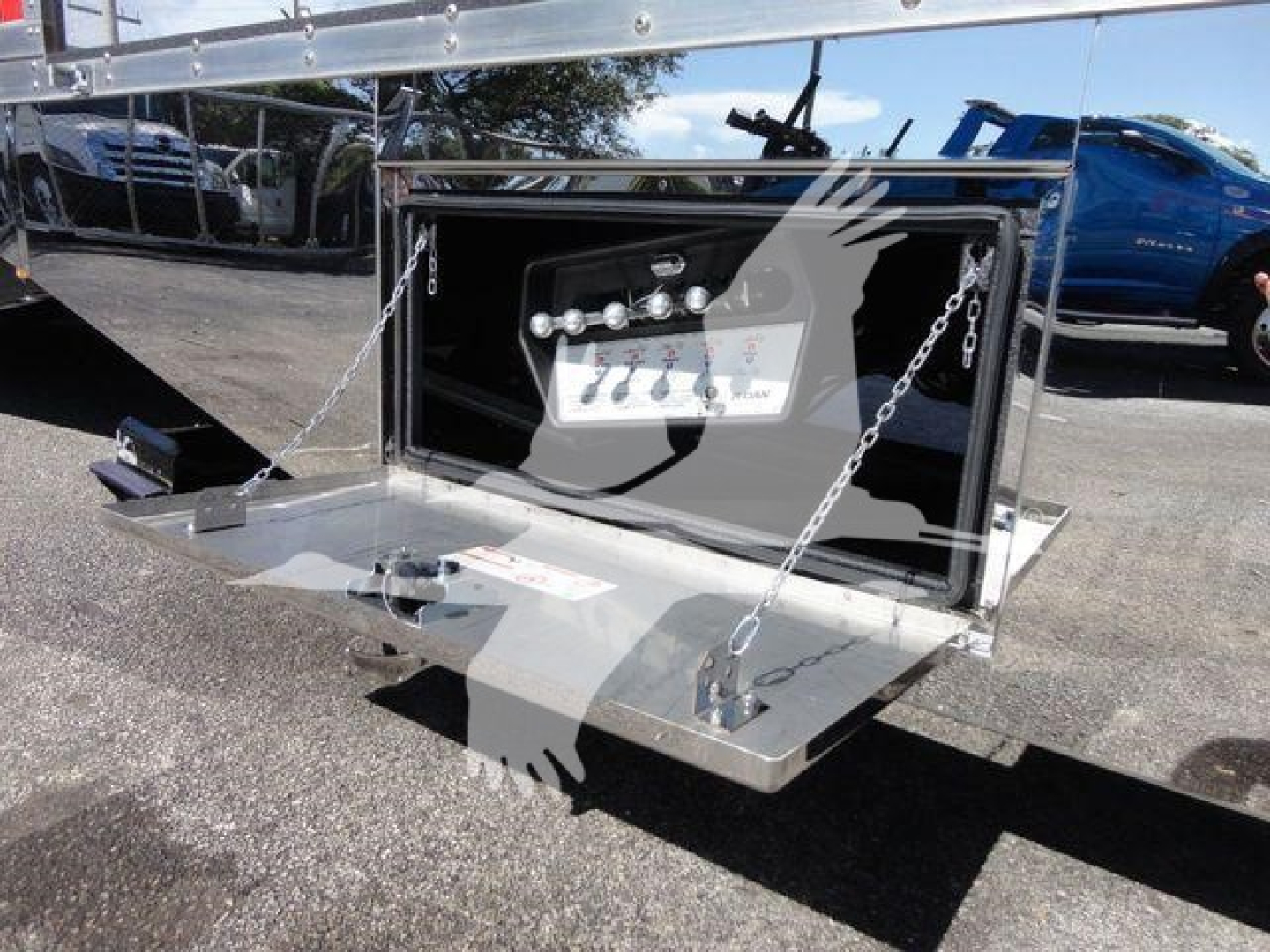 Rear view of a Mack MD6 rollback truck showing a built-in storage box with a control panel and chains on the tailgate.