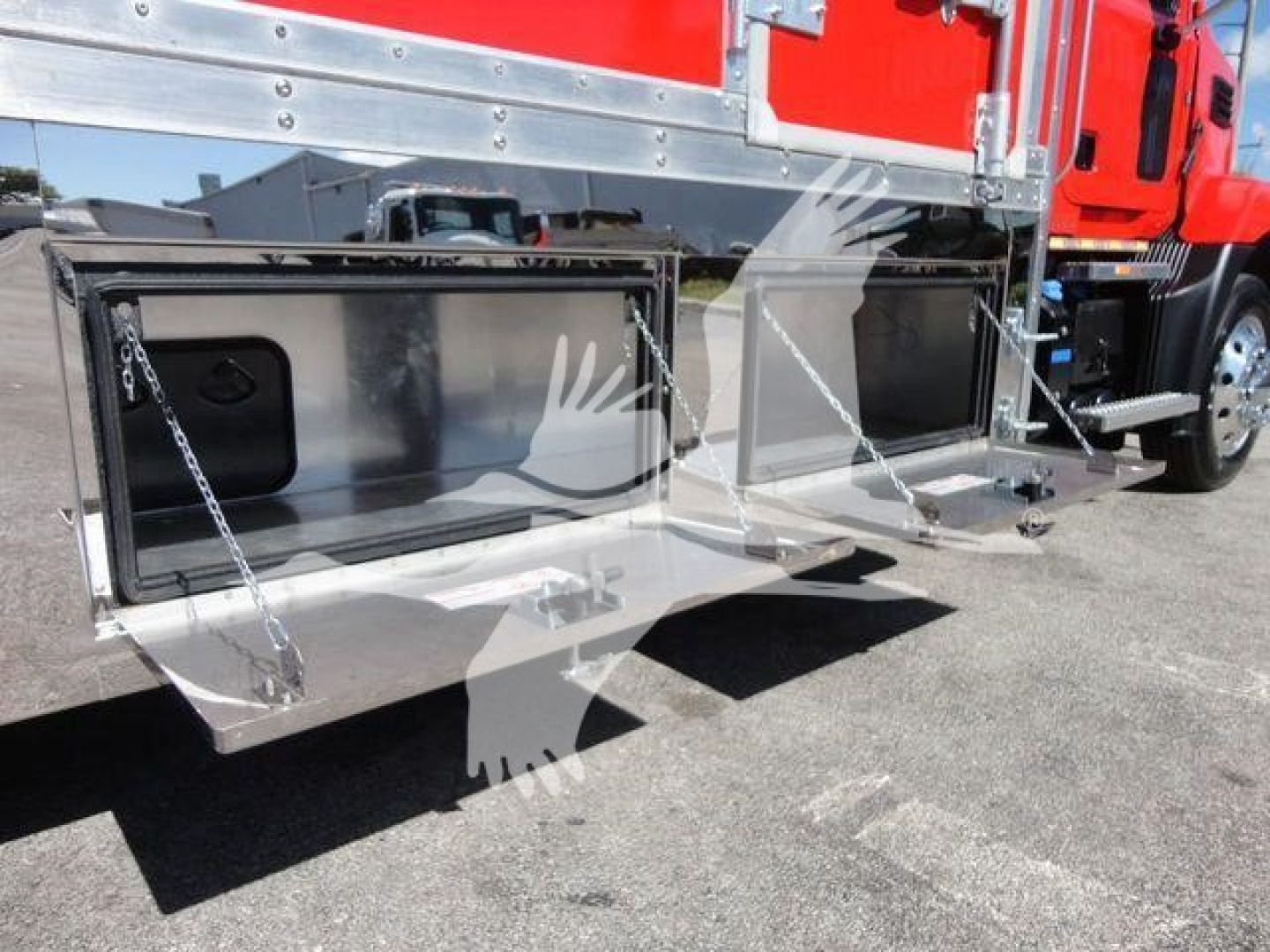 MD6 Mack rollback truck with open storage compartments under body, chrome metal finish, hydraulic rams and chain brackets visible.