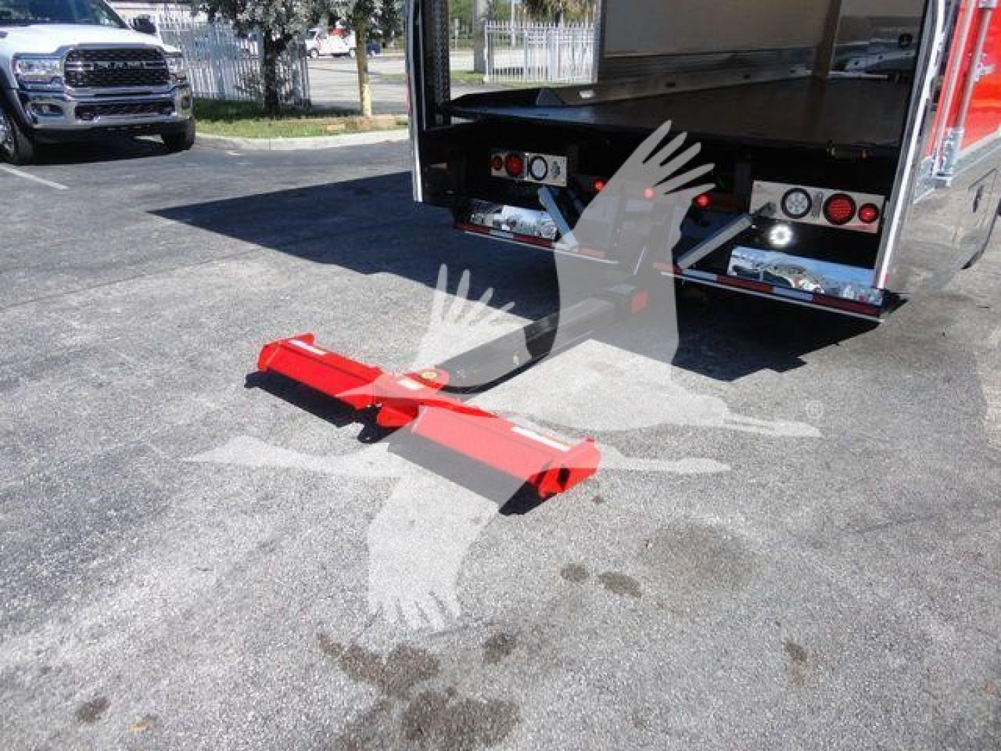 Truck bed of a Mack MD6 rollback with a red wheel-lift/tow bar extending from the rear, visible taillights, and a flatbed area in the background.