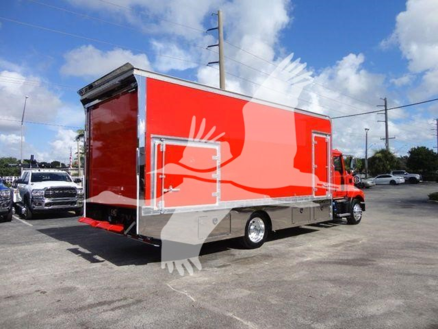 MD6 rollback truck body on a red Mack MD6 chassis, side panel storage compartments visible, dealership lot background.